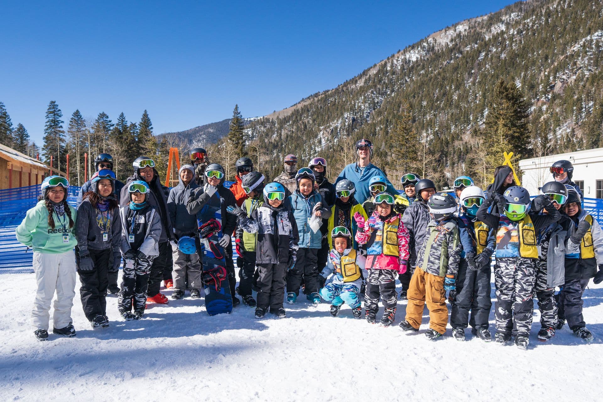 A group of 20+ skiers and snowboarders huddled together