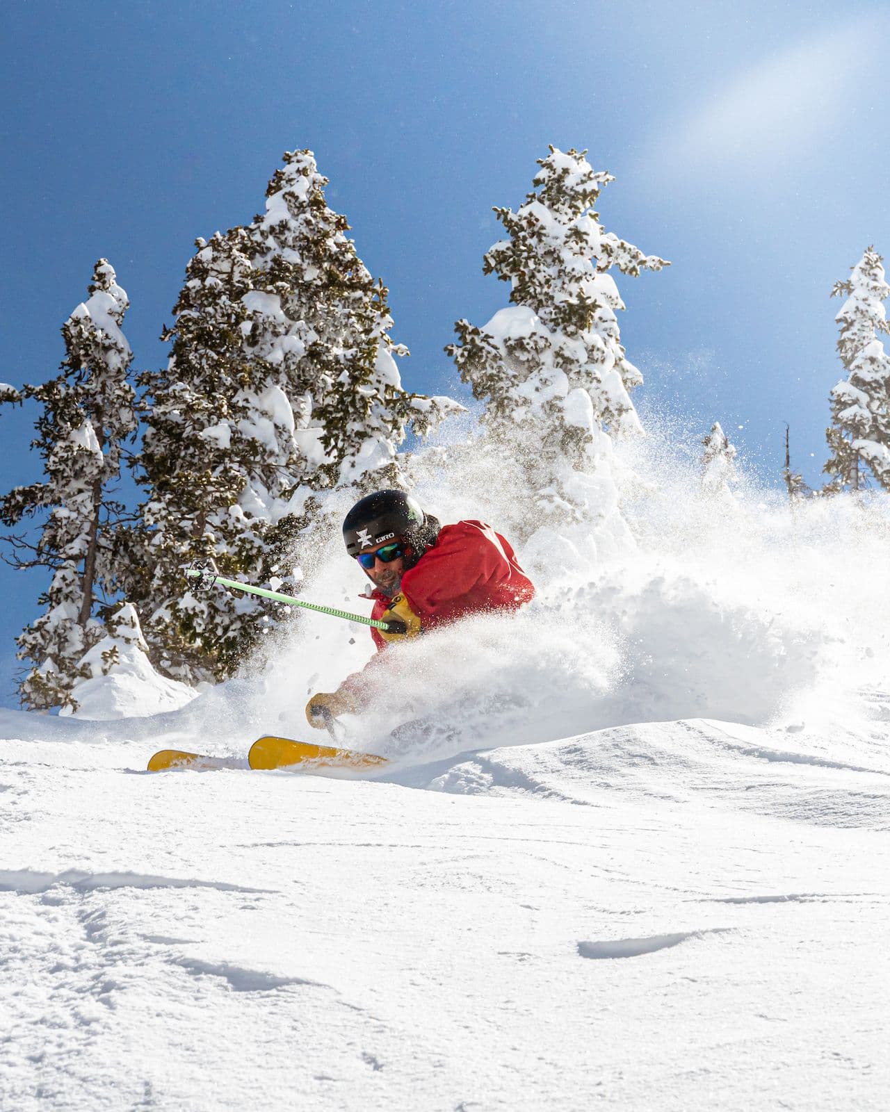 Man skiing in deep powder on a bluebird day in Taos Ski Valley