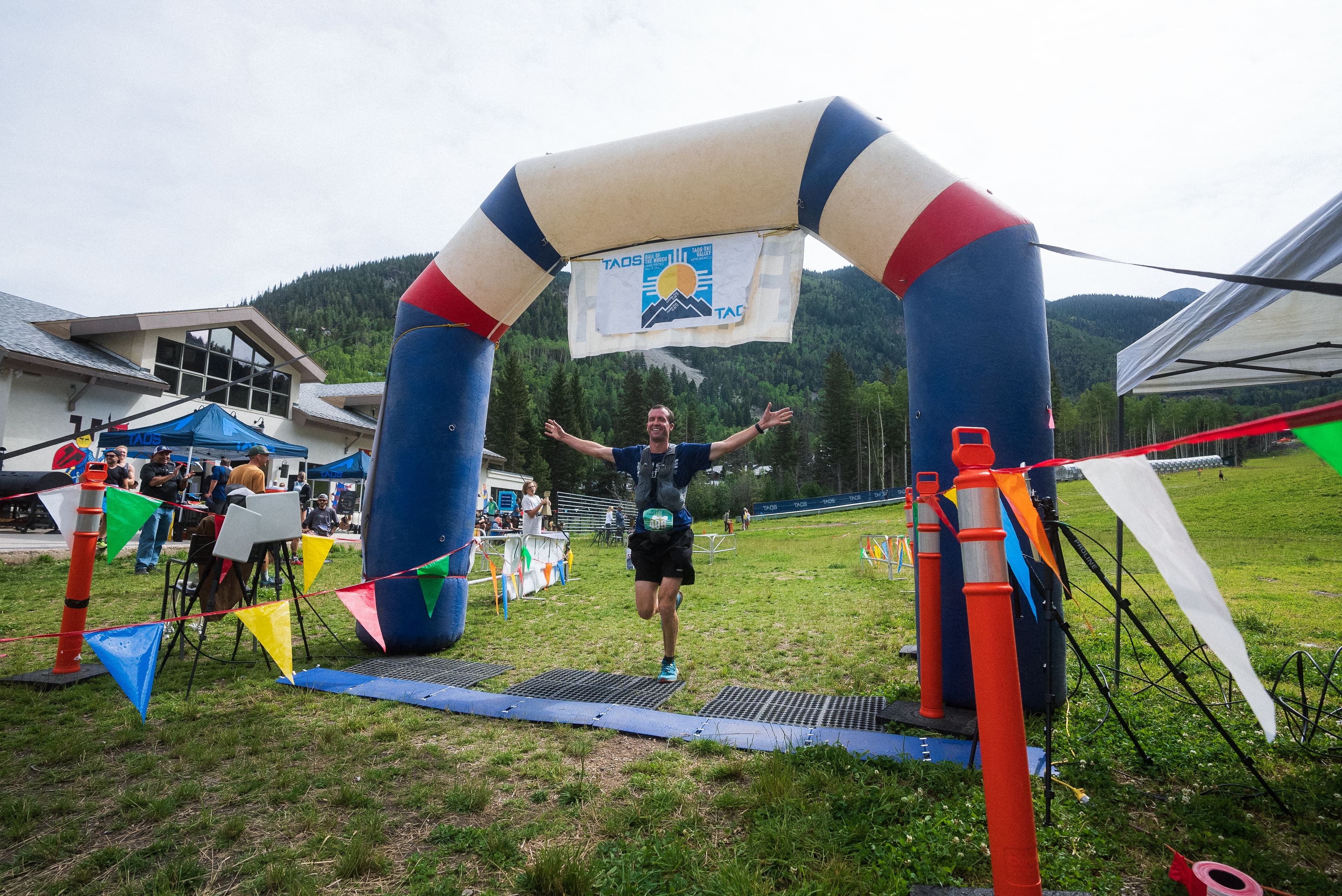 A runner crossing the finish line of a trail race in Taos Ski Valley