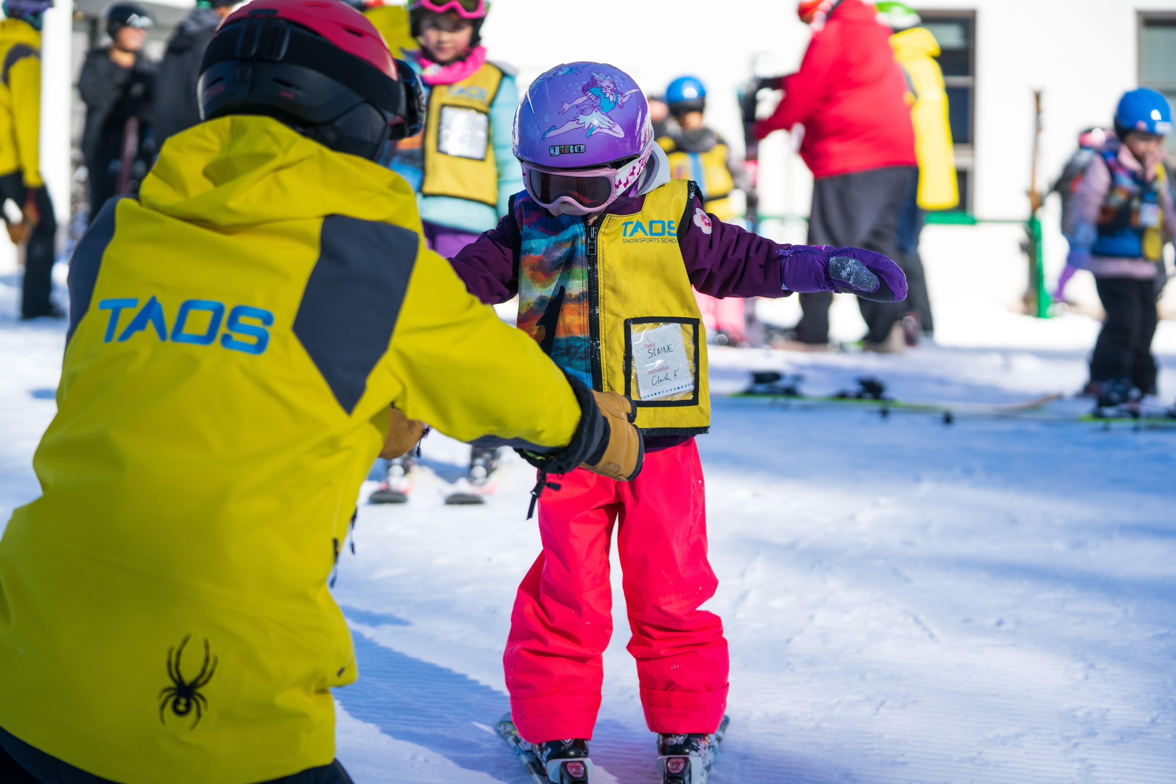 Ski instructor helping a child with their form at Taos Ski Valley.