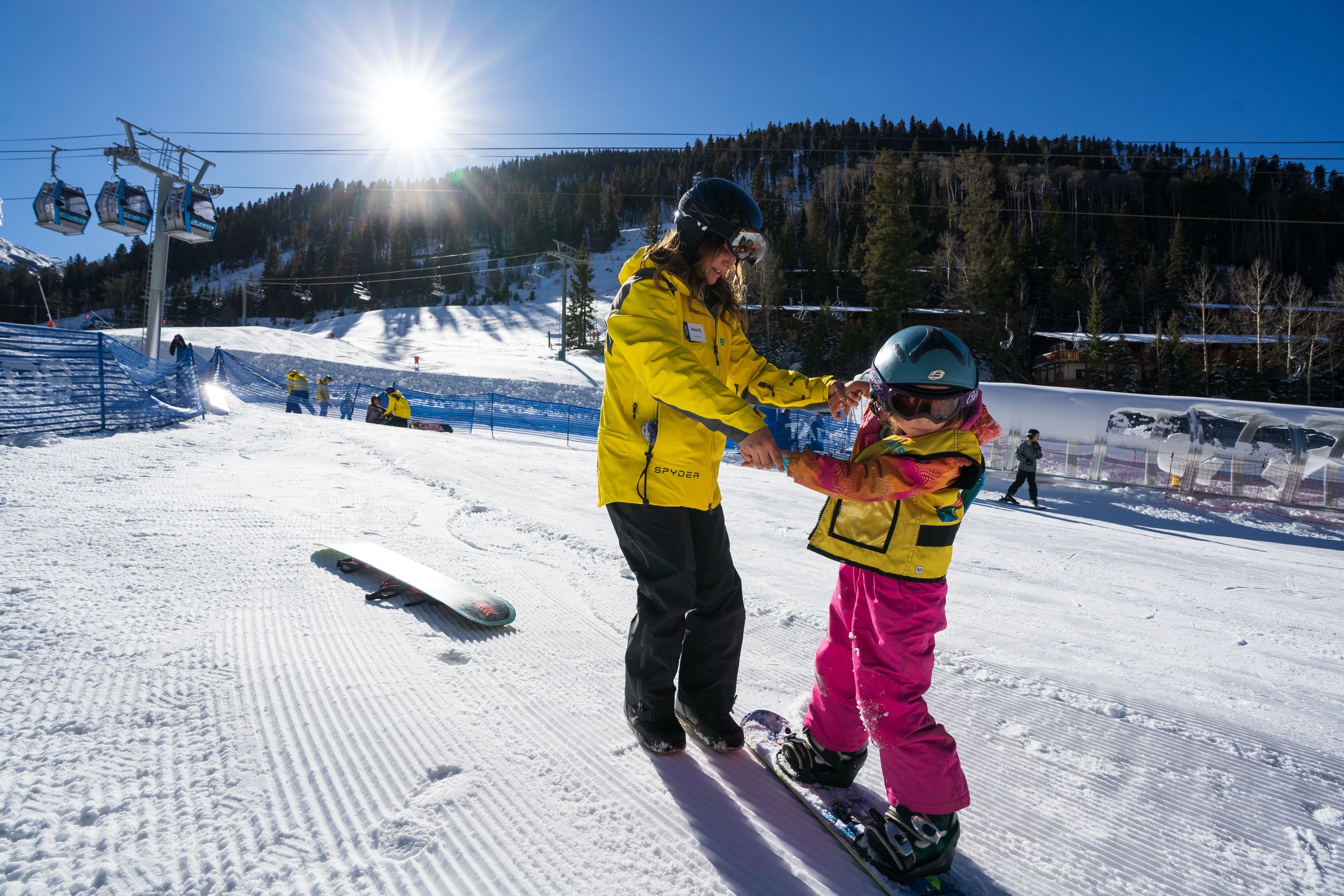 Instructor helping a child learn how to snowboard at Taos Ski Valley.