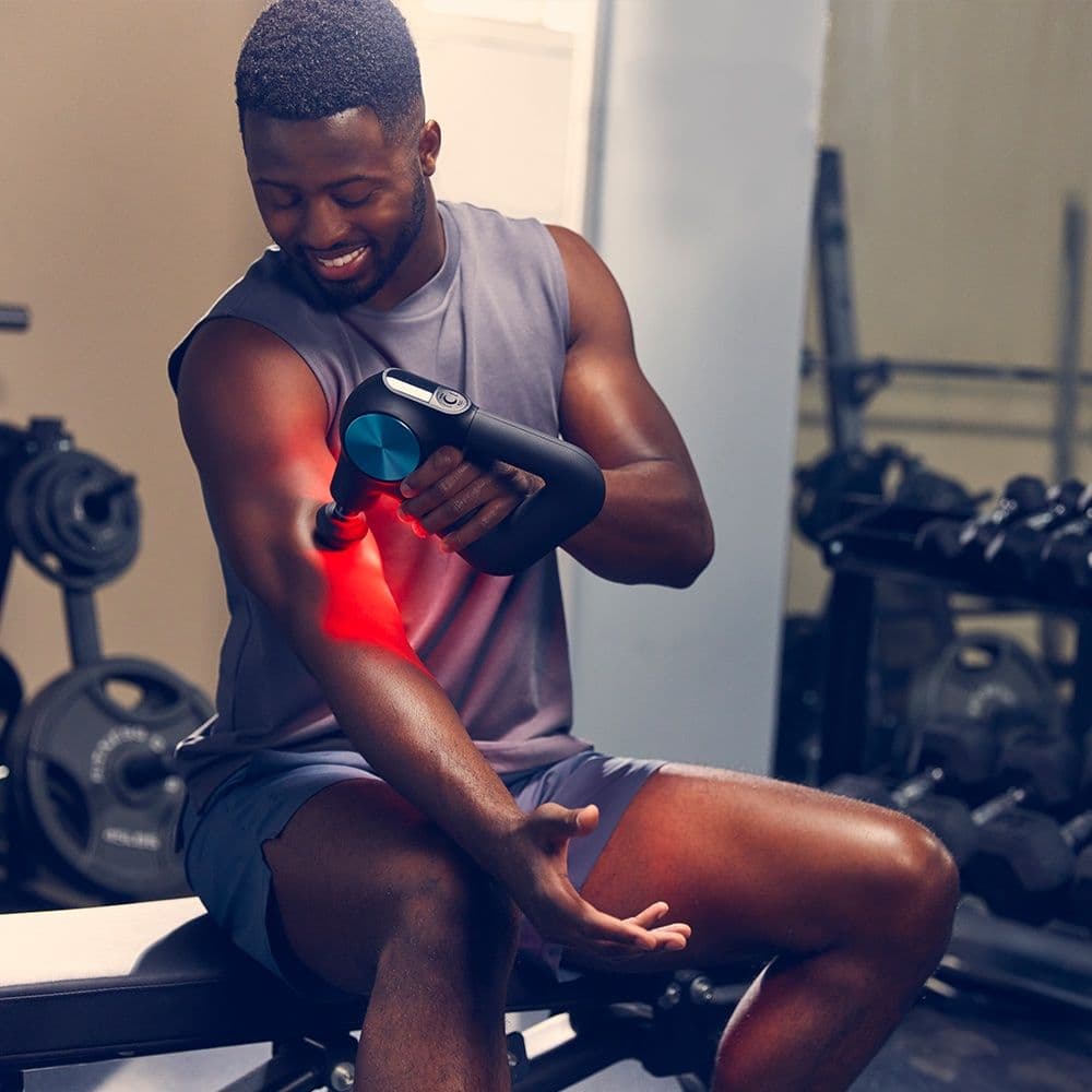 Man using Theragun Pro Plus in a gym