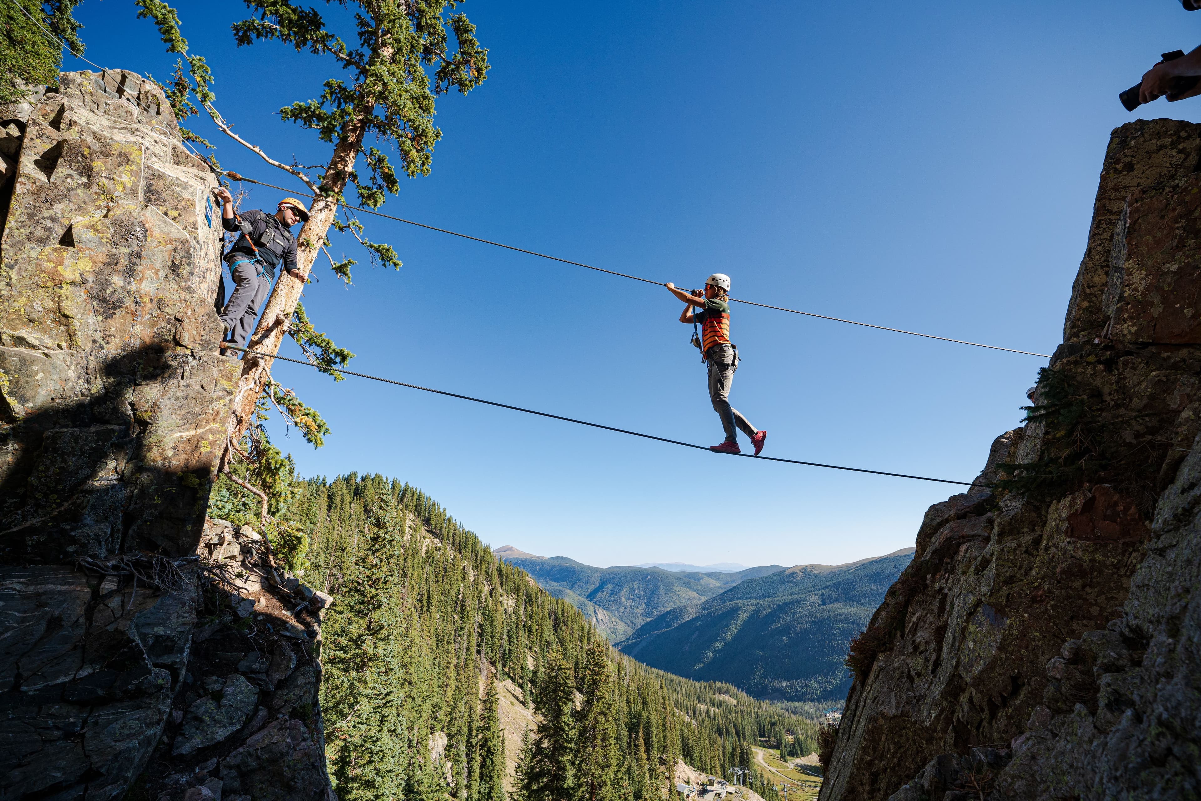 Someone crossing the suspension bridge in full rock climbing gear at Via Ferrata.