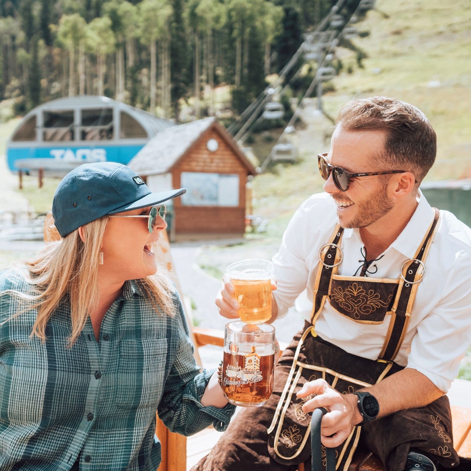 A woman and a man clinking their beer steins at The Bavarian in Taos Ski Valley