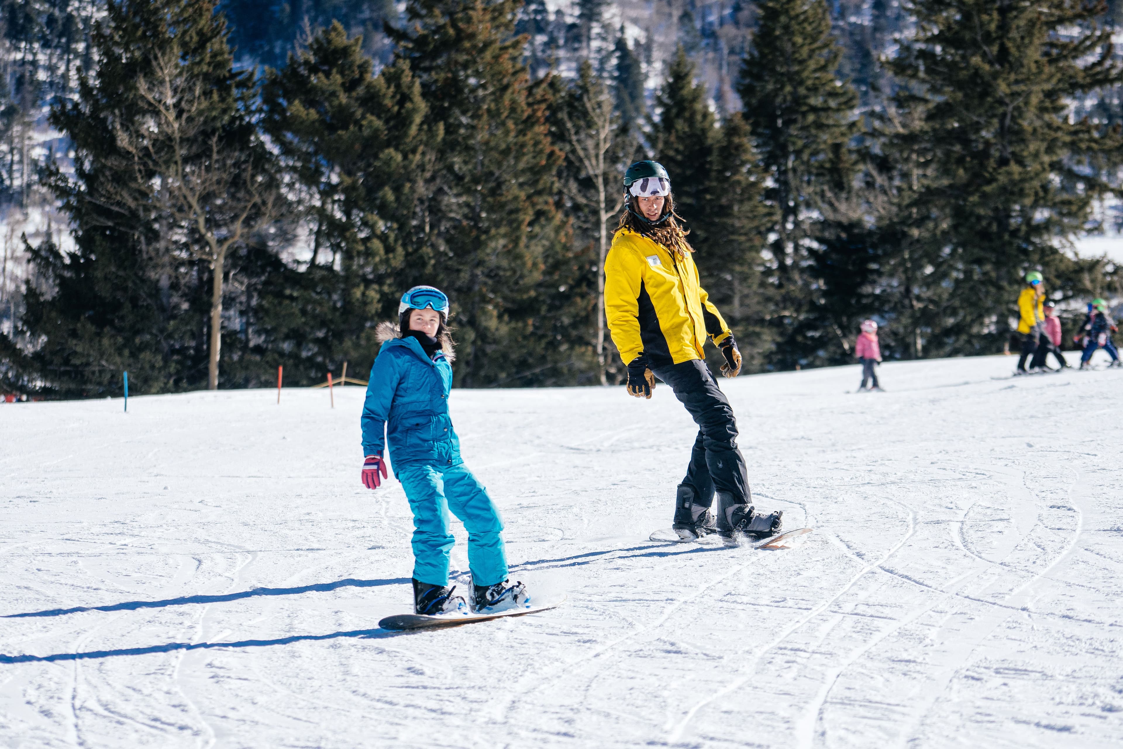 A snowboard instructor teaches a student how to snowboard