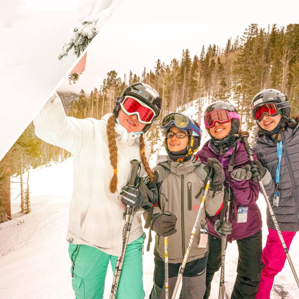 4 teenagers take a selfie in snow gear.