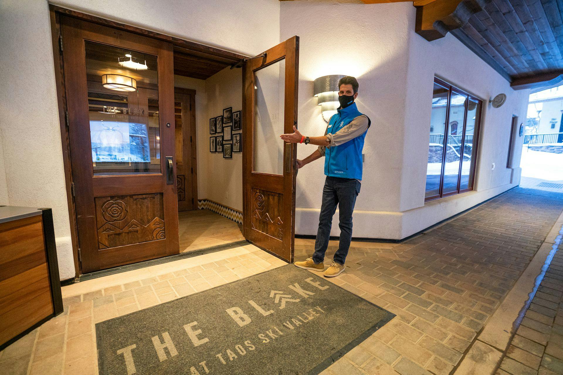 A Blake hausmeister opens the lobby door welcoming guests to the hotel