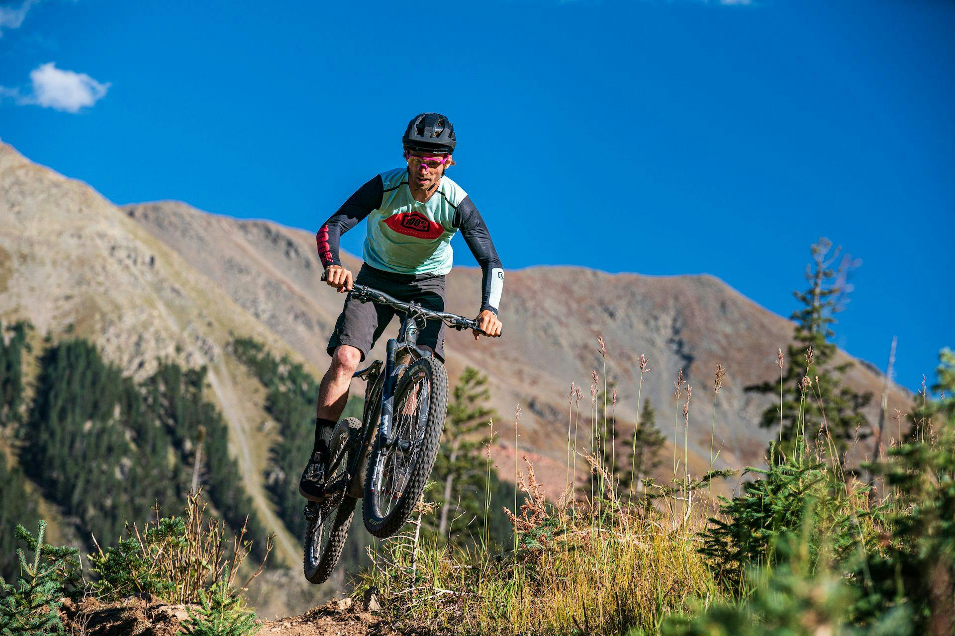 A biker doing a jump on a mountain trail at Taos Ski Valley.