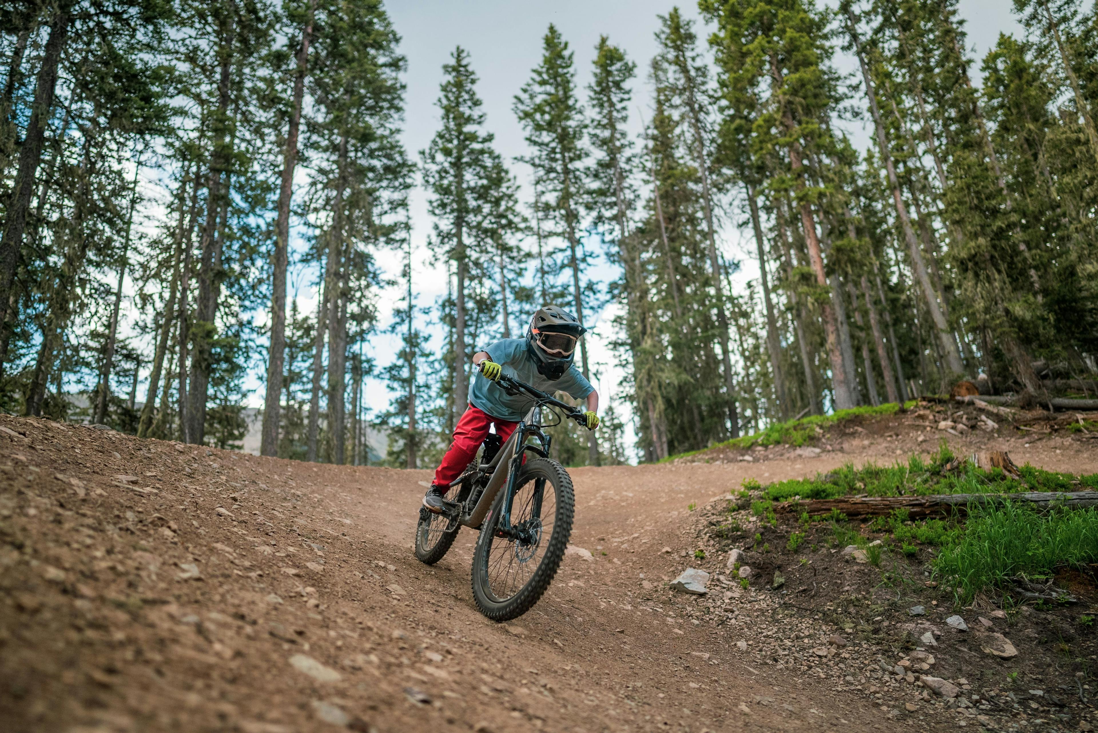 Young mountain biker heads down a trail in the bike park at TAOS Ski Valley