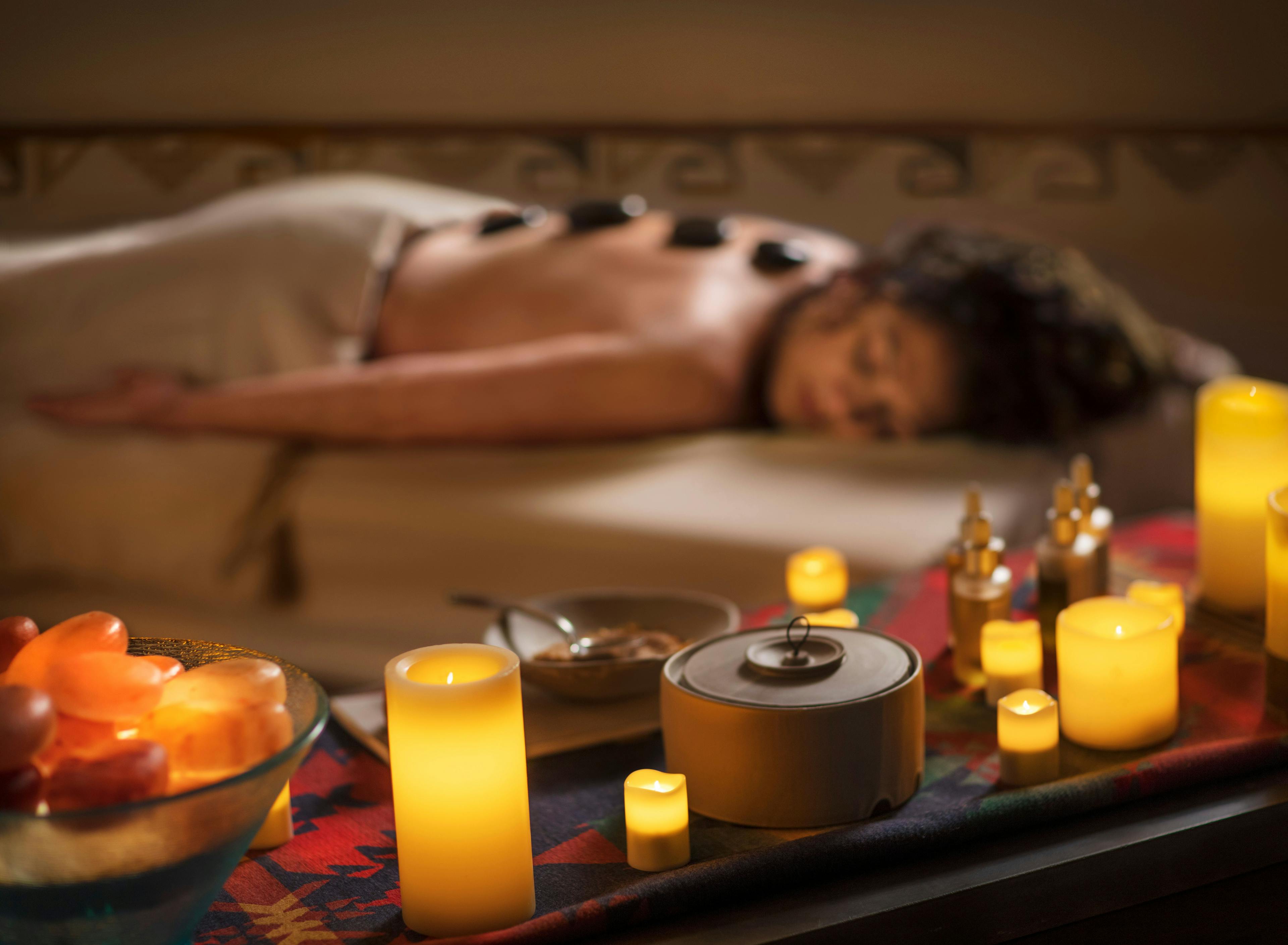 Spa guest enjoy lava stone treatment in a softly lit room